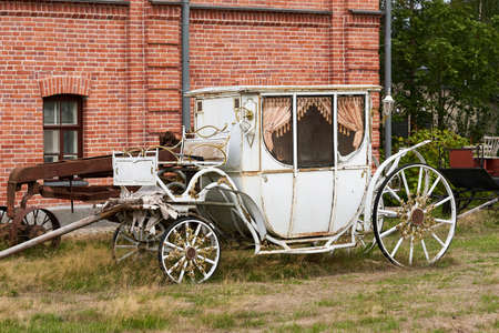 Old white carriage on the background of a red brick building. White vintage carriageの写真素材