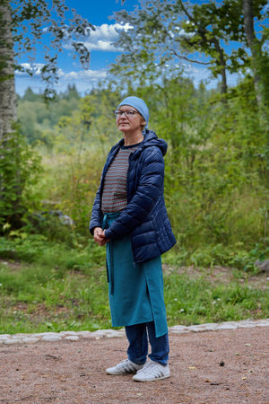 A woman dressed as a religious pilgrim walks along a forest road. Portrait of a pilgrim on a forest roadの写真素材