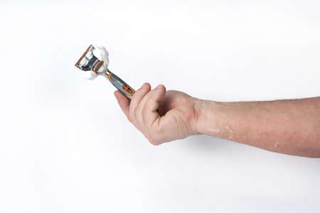 Hand holds a shaving razor with shaving foam on a white backgroundの写真素材