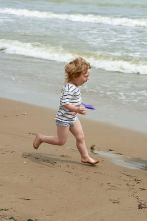A little boy runs along the sandy beach along the seashoreの写真素材