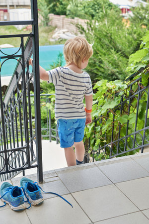 A little boy goes down the stairs to the gardenの写真素材