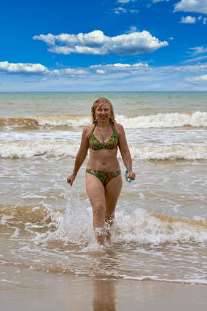 A woman in a swimsuit with white long hair comes out of the seaの写真素材