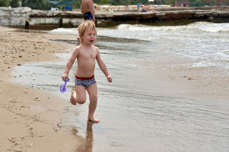 A little boy runs along the sandy beach along the seashoreの写真素材
