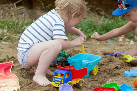 Two children play in the sand with plastic toysの写真素材