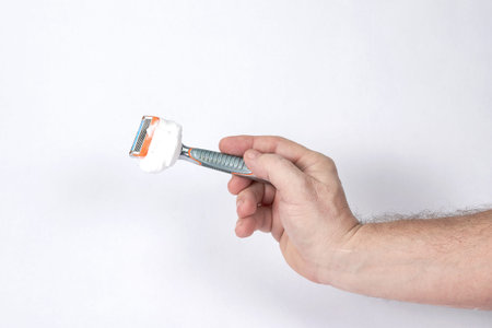 Hand holds a shaving razor with shaving foam on a white backgroundの写真素材