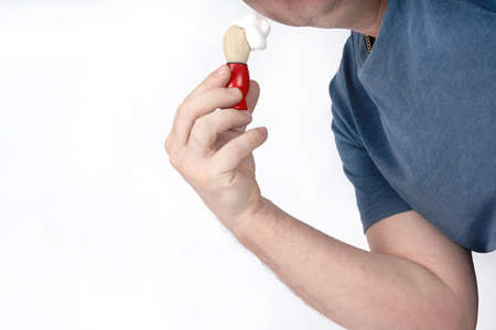 A man applies shaving foam to his face with a shaving brushの写真素材