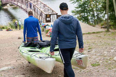 Men carry kayaks to the water, preparing for the competitionのeditorial素材