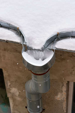 Snow and frozen water blocked the drain on the roof of the old houseの写真素材