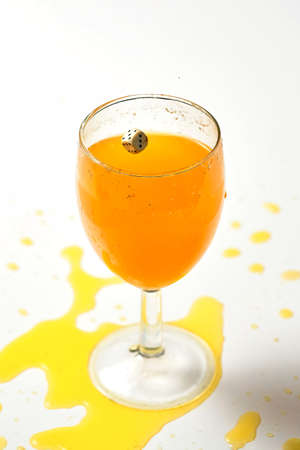 Splash of orange liquid in a glass from a thrown diceの写真素材