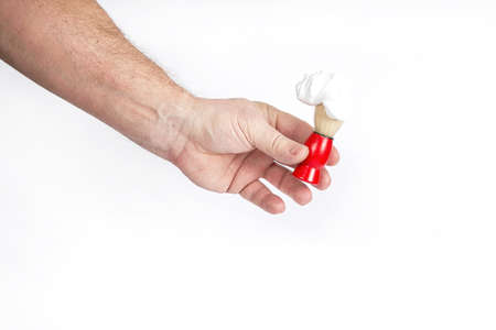 Hand holds a shaving brush with shaving foam on a white backgroundの写真素材