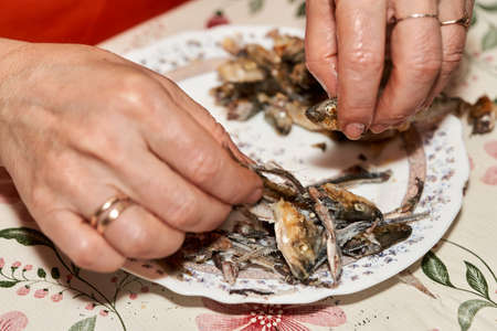 Hands cut fried fish smelt separating the flesh from the bonesの写真素材