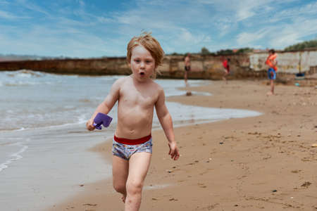 A little boy runs along the sandy beach along the seashoreの写真素材
