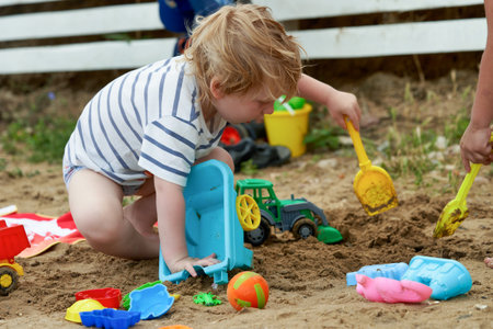 Little boy plays in the sand with plastic toysの写真素材