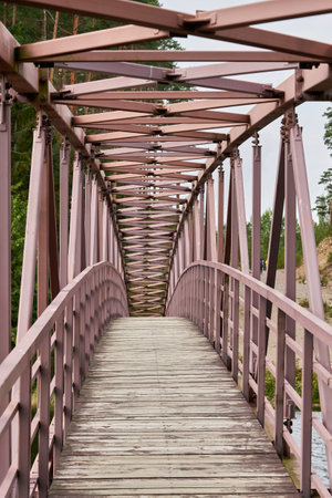 An arched pedestrian bridge over the river with a wooden deckの写真素材