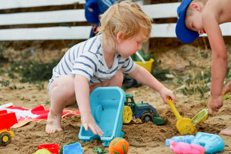 Two children play in the sand with plastic toysの写真素材