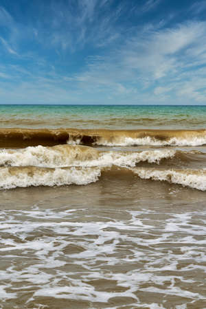 Large waves with foam on the sea coast against the background of the skyの写真素材
