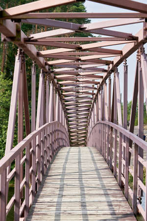 An arched pedestrian bridge over the river with a wooden deckの写真素材