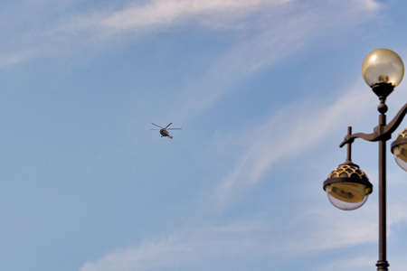 Flying helicopter against the background of a blue sky with spruce cloudsの写真素材
