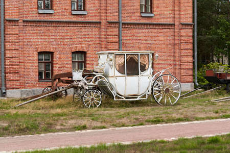 Old white carriage on the background of a red brick buildingの写真素材