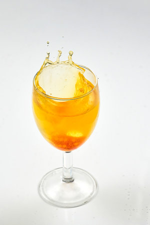 A dice falling into a glass of orange liquid caused a splashの写真素材