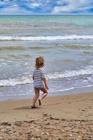 A little boy runs along the sandy beach along the seashoreの写真素材