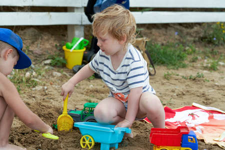 Two children play in the sand with plastic toysの写真素材