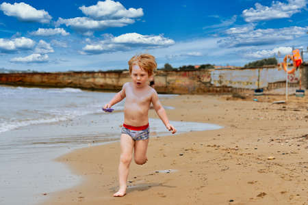 A little boy runs along the sandy beach along the seashoreの写真素材