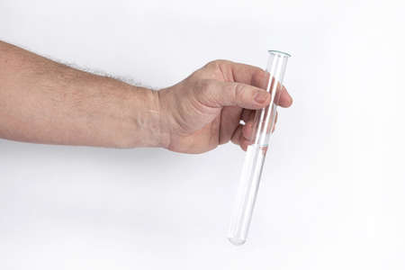 Hand holds a glass test tube with a transparent liquid on a white backgroundの写真素材