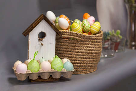 Multicolored easter eggs on the background of a wooden bird houseの写真素材