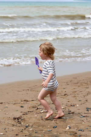 A little boy runs along the sandy beach along the seashore. Child resting on the seaの写真素材