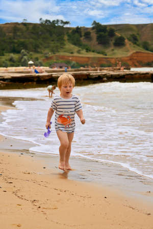 A little boy runs along the sandy beach along the seashoreの写真素材