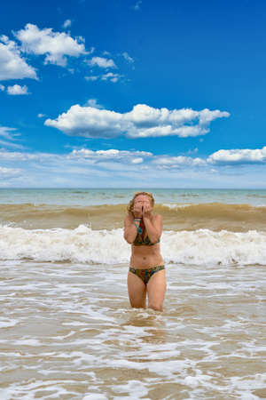 A woman in a swimsuit with white long hair comes out of the seaの写真素材