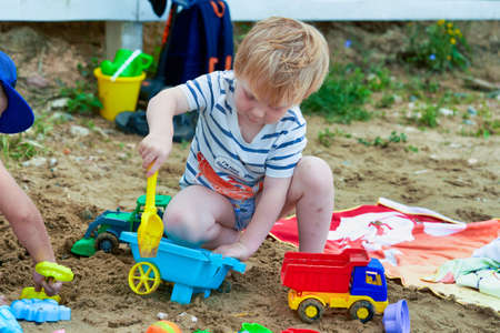 Little boy plays in the sand with plastic toysの写真素材
