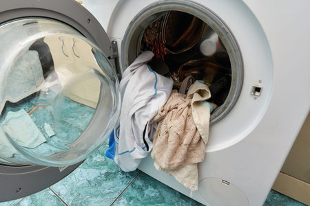 Washing machine with an open door and dirty laundry placed in the washing drumの写真素材