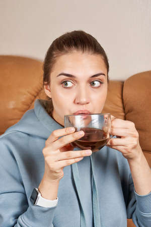 Beautiful brunette with slicked back long hair drinks coffeeの写真素材
