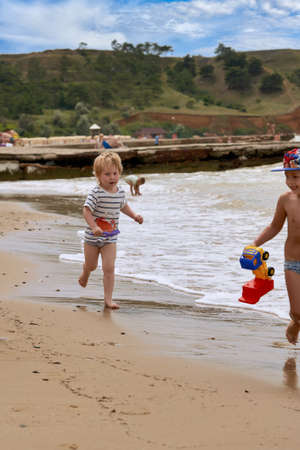 A little boy runs along the sandy beach along the seashoreの写真素材