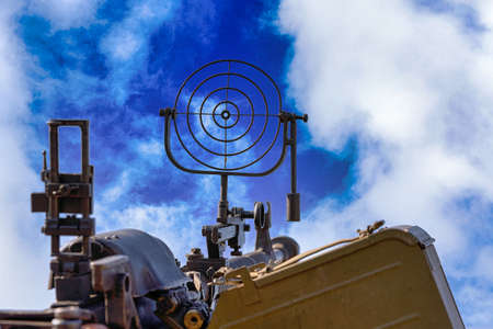 fragment of an anti aircraft machine gun, a round sight is aimed at clouds skyの写真素材