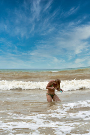 A woman in a swimsuit with white long hair comes out of the seaの写真素材