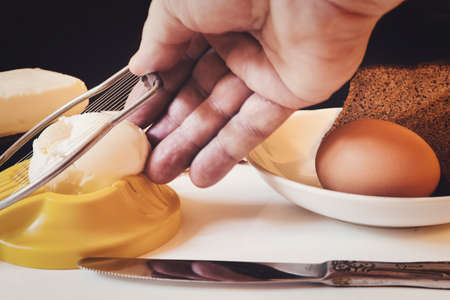 Hand controls an egg cutter on the background of products for making a sandwichの写真素材