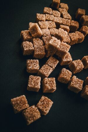Brown cane sugar in cubes on a black background. Still life.の写真素材