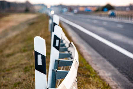 Black and white signal road posts on an asphalt road. Country road and fence.