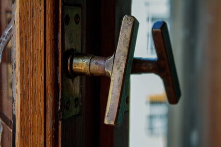 Old handle with a lock in a white door, reflected in the mirror. Peeling paint. Pleasant light in the interior.の写真素材