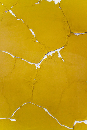 Old yellow textured wall with cracks in white.