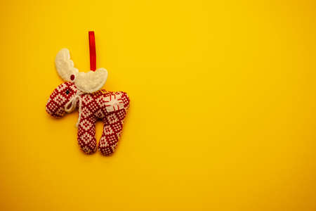 Toy, knitted red deer on a yellow background. Christmas toy for the holiday. High quality photoの写真素材