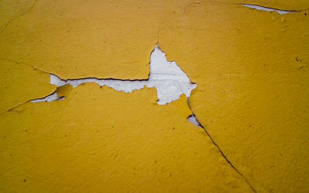 Old yellow textured wall with cracks in white. Beautiful background. Cracked paint of the building. High quality photoの写真素材