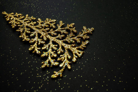 New Year tree on a black background. A festive gift for Christmas. Golden toy for the Christmas tree. Beautiful background for your desktop. High quality photoの写真素材