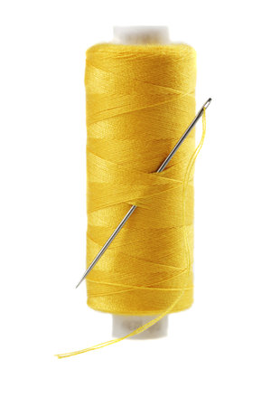 Yellow bobbin of thread with needle isolated on white