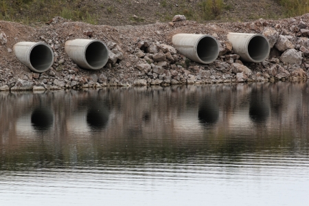 four pipes on waterside pointed to the riverの写真素材