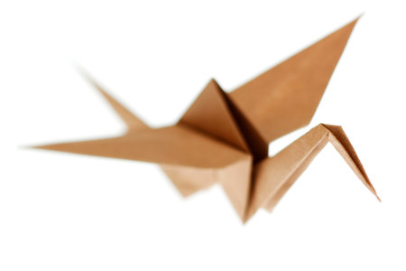 Origami crane bird made from brown recycle paper. Isolated on white backgroundの写真素材
