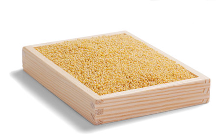 yellow millet in a wooden box on whiteの写真素材